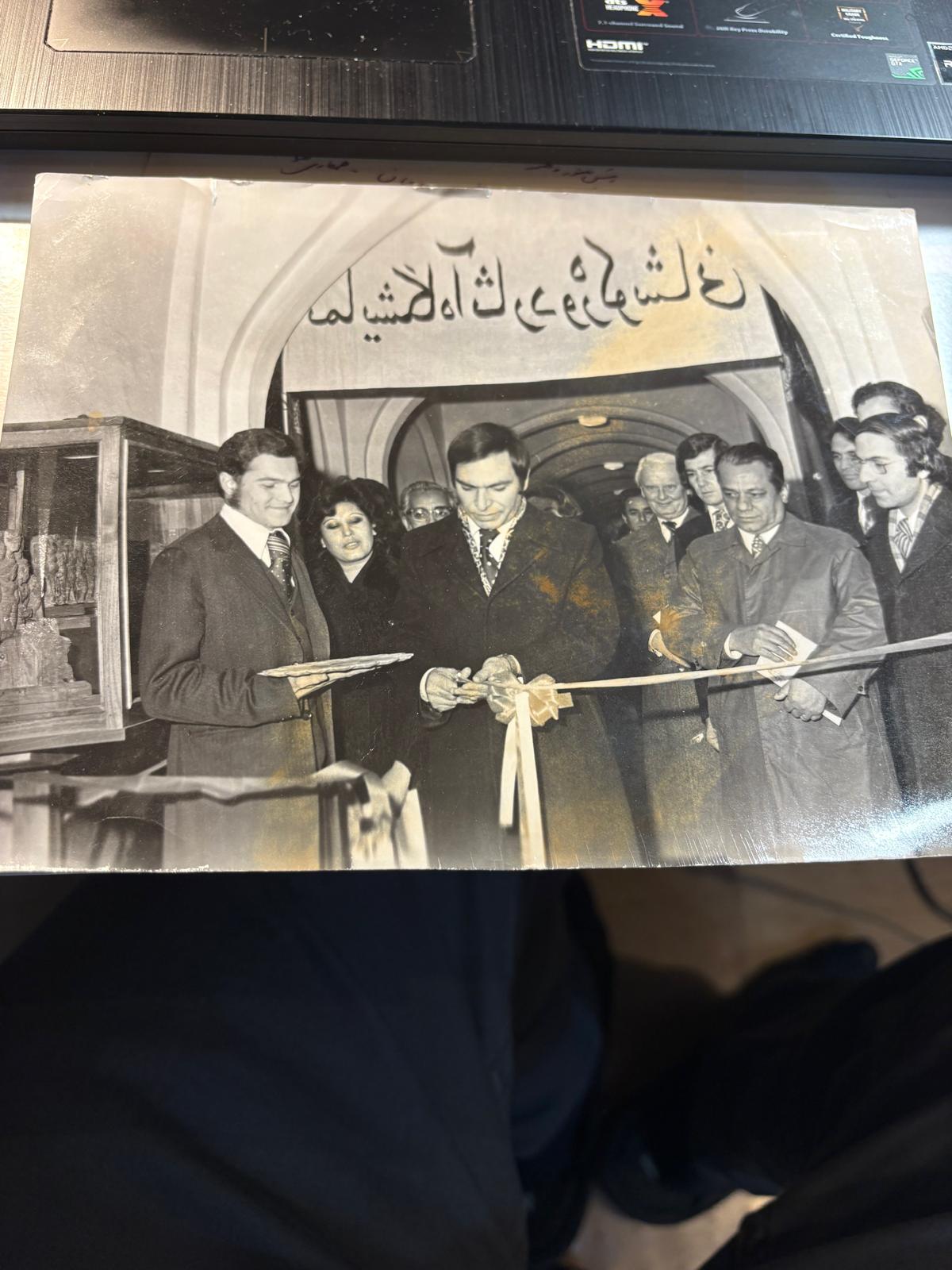 افتتاح نمایشگاه کوشانی از راست به چپ . جناب دکتر رهین، والی کابل که نامش فراموشم شده، جناب بشیر وهاب زاده معین اطلاعات و نشرات، خانم کنار وهاب زاده نام او فراموشم شده و خودم در عقب آقای اسحاق محمود و سفیر آلمان در کابل دیده میشود.